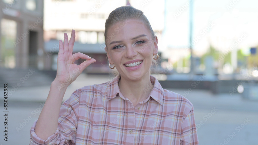 Young Woman showing Ok Sign with Finger Outdoor