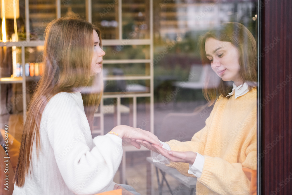 A beautiful girl shows her engagement ring to her friend at a friendly get-together. Two young women are discussing wedding preparations. A beautiful girl shows her engagement ring to her friend at a friendly get-together. Two young women are discussing wedding preparations.