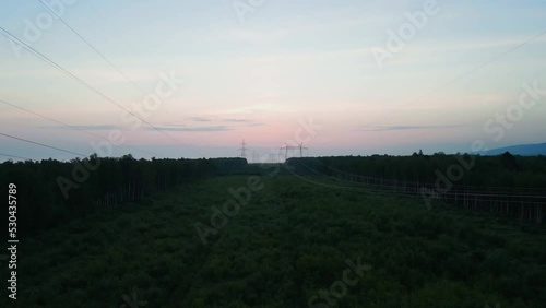 direct flight over high-voltage pylons and wires over the green bushes against the sky of twilight colors photo