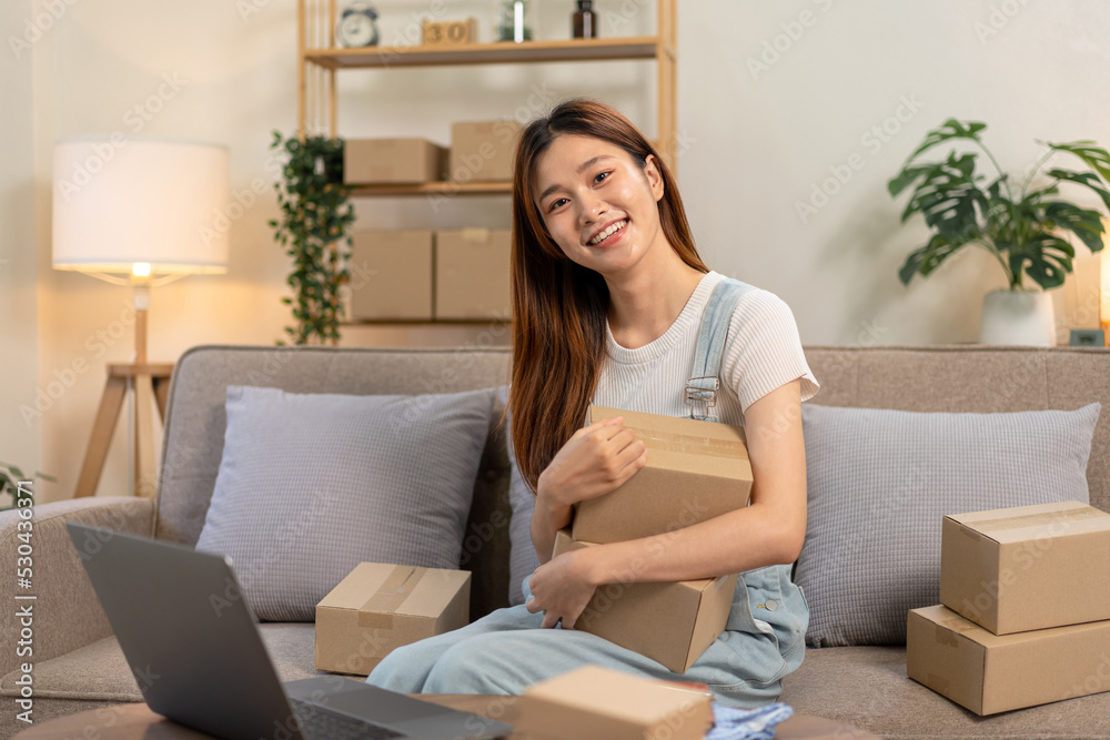 Young entrepreneur holding and hug cardboard boxes to preparing for home delivery to customers while sitting Young entrepreneur holding and hug cardboard boxes to preparing for home delivery to customers while sitting