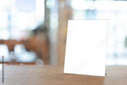 Restaurant menu frame with white blank screen on wooden table in restaurant or cafe on bokeh background