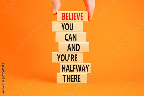 You can symbol. Concept words Believe you can and you are halfway there on wooden blocks on a beautiful orange table orange background. Businessman hand. Business motivational and you can concept. photo