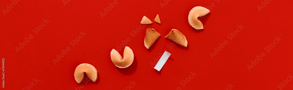 Obraz premium Fortune cookies on red background with deep long shadows. Blank paper for prediction words