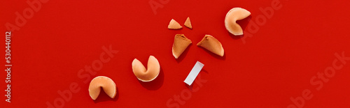 Fortune cookies on red background with deep long shadows. Blank paper for prediction words