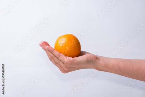 hand holding an orange, fruits and vegetables, healthy living, lifestyle