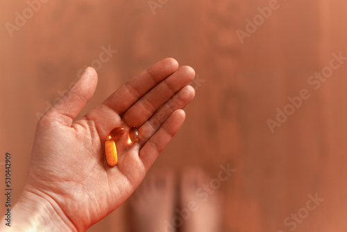 Female hand holding daily dose of vitamins. Omega 3 and complex pills. First person perspective, POV, flat lay. High quality photo