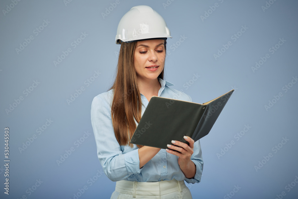 Woman engineer in protective helmet looking on book. Isolated female portrait.