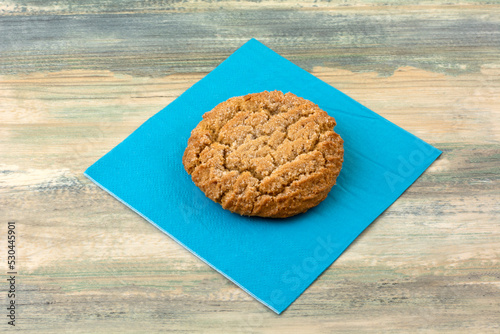 One baked chewy ginger cookie on blue napkin on table