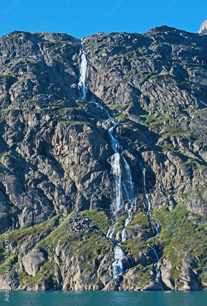 Obraz premium With mountains, glaciers and this beautiful waterfall, Prince Christian Sound in southern Greenland. Greenland offers tranquil waters and spectacular views.
