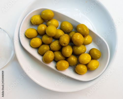 Bunch of green olives served on plate. Appetizer on table