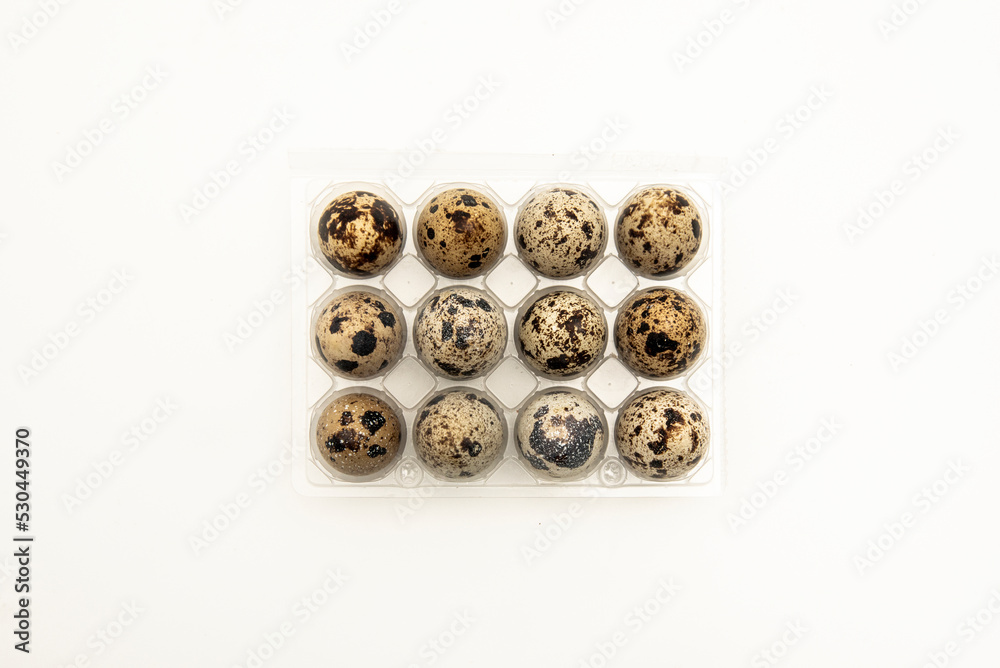 A dozen small quail eggs in a clear plastic container A dozen small quail eggs in a clear plastic container