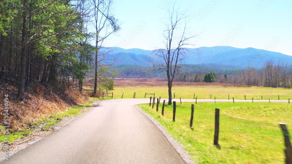 Pov point of view car vehicle shot driving on Cades Cove scenic loop road drive by green pasture field at Great Smoky Mountains National Park, Gatlinburg Tennessee in spring