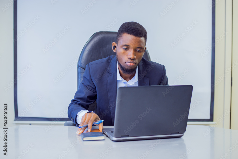 A man in a suit in the office with a laptop A man in a suit in the office with a laptop