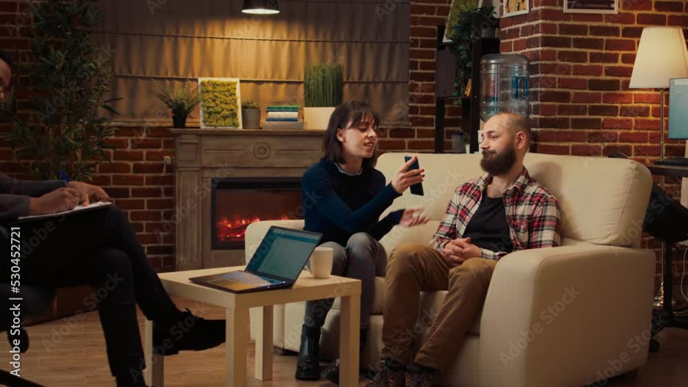 Woman showing text messages proof of adultery, husband caught cheating on wife. Showing smartphone conversation and talking about infidelity with specialist at therapy session.
