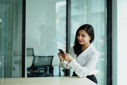 Portrait of a young Asian woman sitting at a desk using her phone Free Download Portrait of a young Asian woman sitting at a desk using her phone - GFXLoad