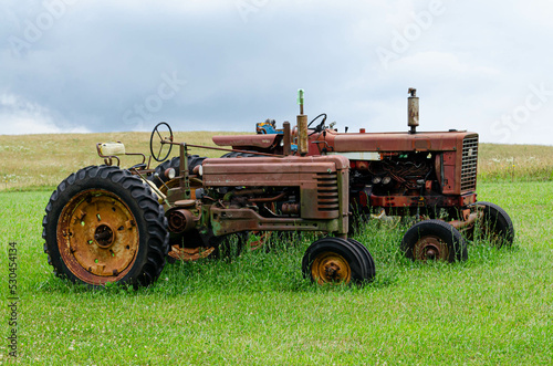 A pair of old rusty tractors in a field

