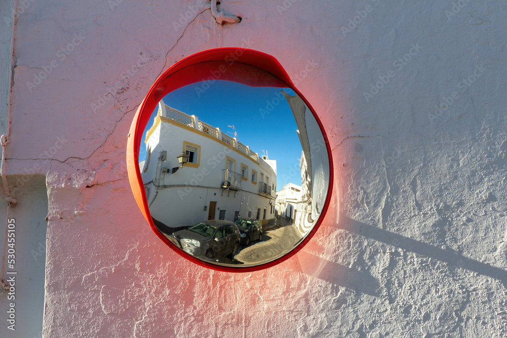 Convex mirror on white wall at crossroads