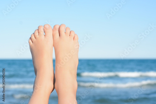 Child resting near sea, closeup of feet. Space for text