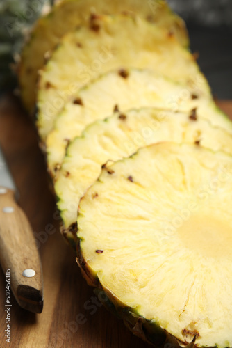 Tasty cut pineapple and knife on wooden board, closeup