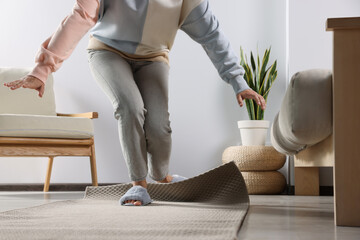 Woman tripping over carpet at home, closeup
