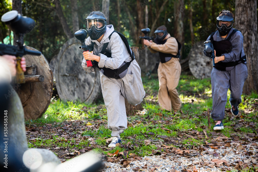 Fototapeta premium Group of people in full gear playing paintball on shooting range