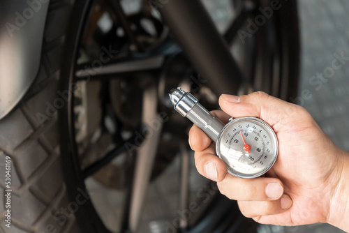 Man holding pressure gauge for checking motocycle tyre pressure ,maintenance,repair motorcycle concept in garage .selective focus