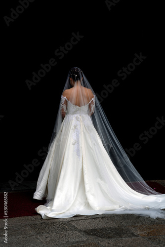 Bride wearing white wedding dress with black background.