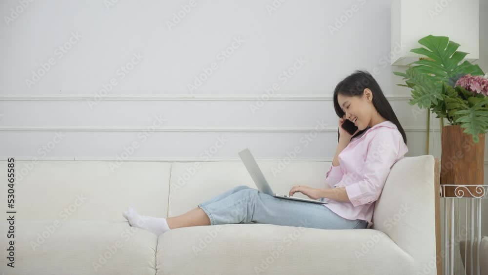Young asian business woman working on laptop computer and calling talking smart phone with cozy at home, female speaking telephone and using notebook with relax, business and lifestyles concept. Young asian business woman working on laptop computer and calling talking smart phone with cozy at home, female speaking telephone and using notebook with relax, business and lifestyles concept.