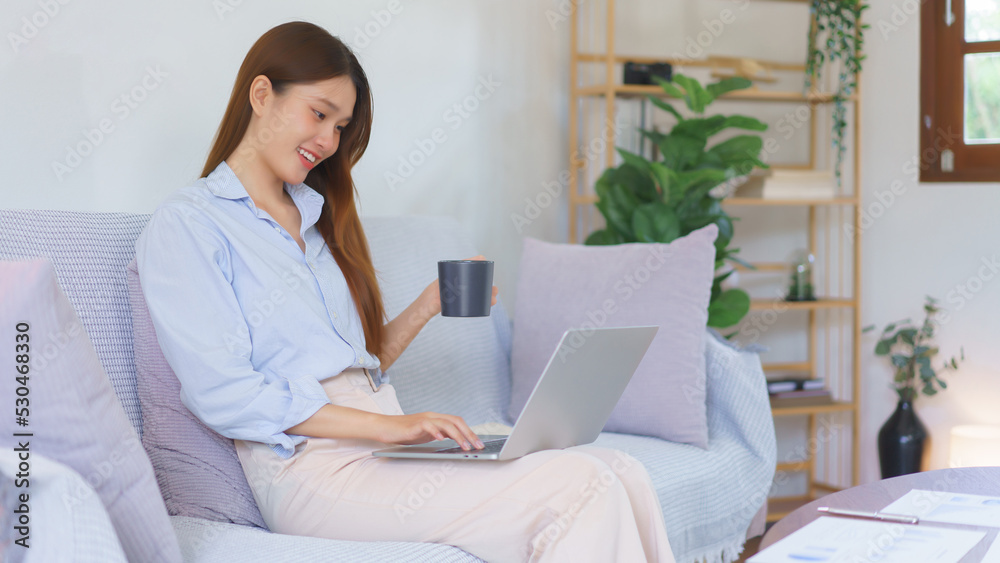 Remote business concept, Businesswoman is reading marketing plan data on laptop and drinking coffee Remote business concept, Businesswoman is reading marketing plan data on laptop and drinking coffee