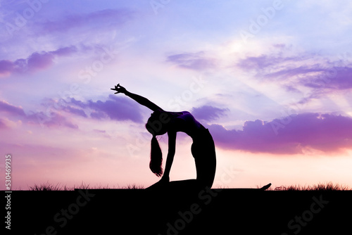 Valokuva The slender girl is doing a yoga warm-up exercise outdoors