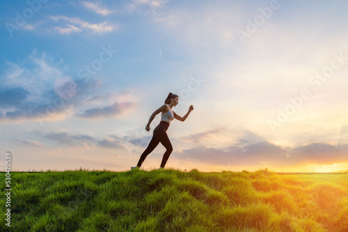 The silhouette of the back of a girl jumping and running in the morning glow