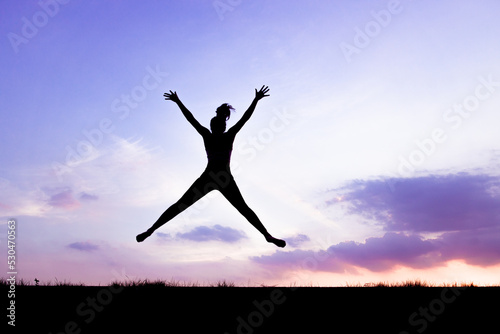 The silhouette of the back of a girl jumping and running in the morning glow