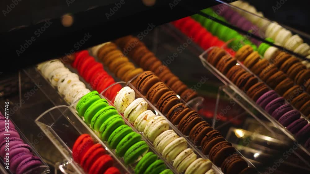 View into glass display case of colorful macarons in dimly lit, high-end bakery View into glass display case of colorful macarons in dimly lit, high-end bakery