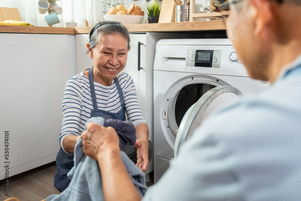 Obraz premium Asian senior couple doing house working and chores in kitchen at home.