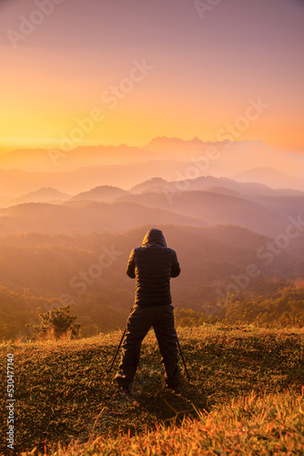 silhouette of a photographer shoots a sunrise in the high mountains. Sunrise, sunset and landscape sky in outdoor beautiful.