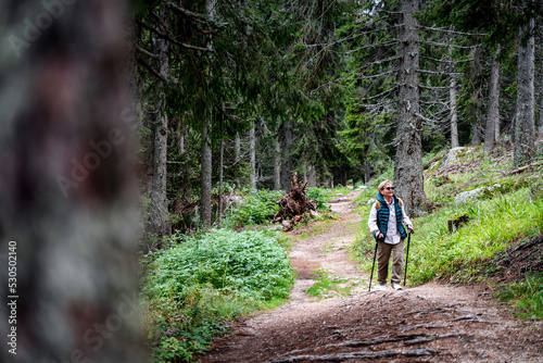 Active happy mature senior woman walking in beautiful autumn forest