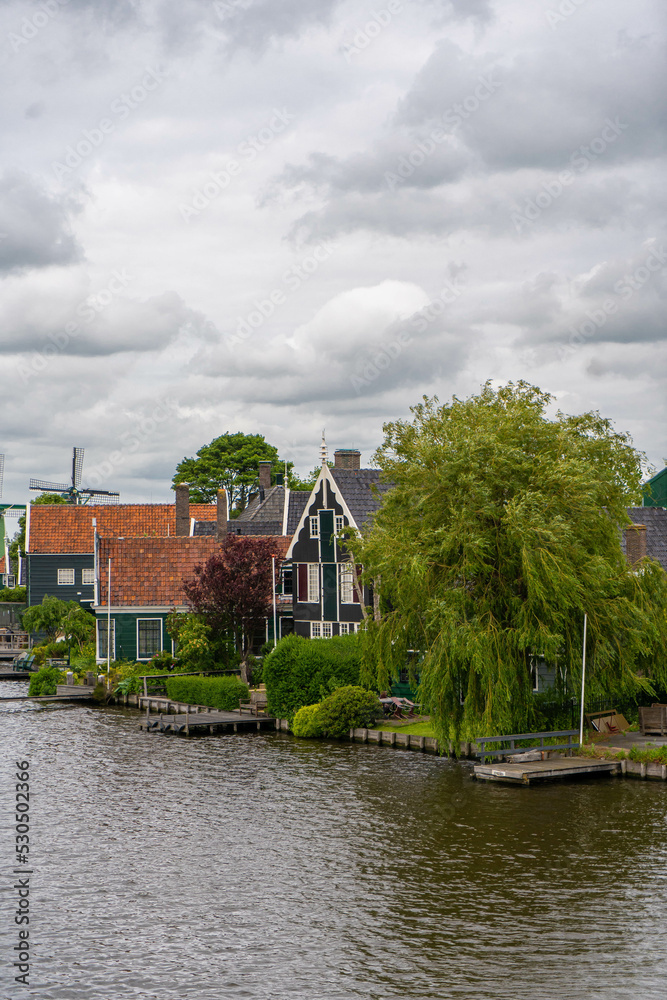Fototapeta premium Rural landscape with windmill in Zaanse Schans. Holland, Netherlands. Authentic Zaandam mill. Beautiful Netherland landscape.