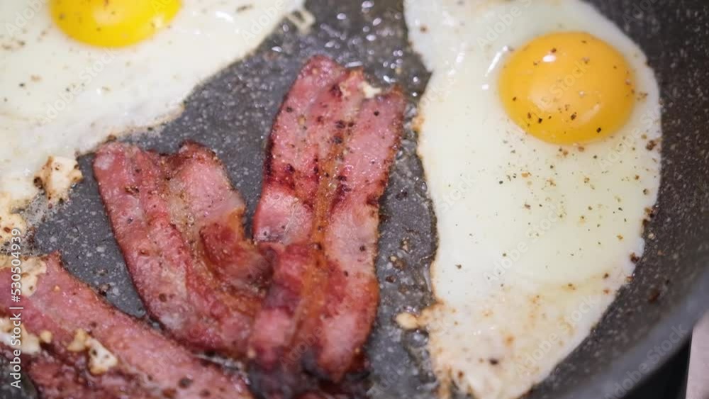 cooking tasty breakfast - fried bacon slices and egg on a frying pan cooking tasty breakfast - fried bacon slices and egg on a frying pan