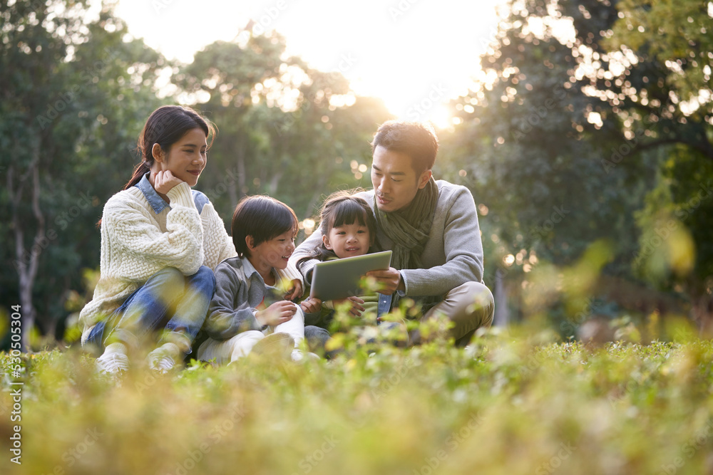 happy asian family having a good time outdoors in city park