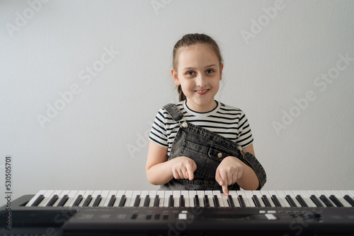Child playing piano. Kids play music. Classical education for children. Art lesson. Little girl at white digital keyboard. Instrument for young student. Music class in school or at home. High quality