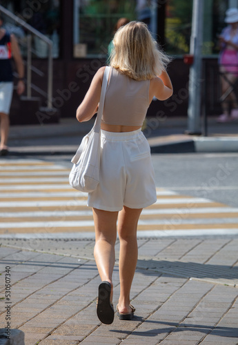 A girl in white shorts walks along a pedestrian crossing.