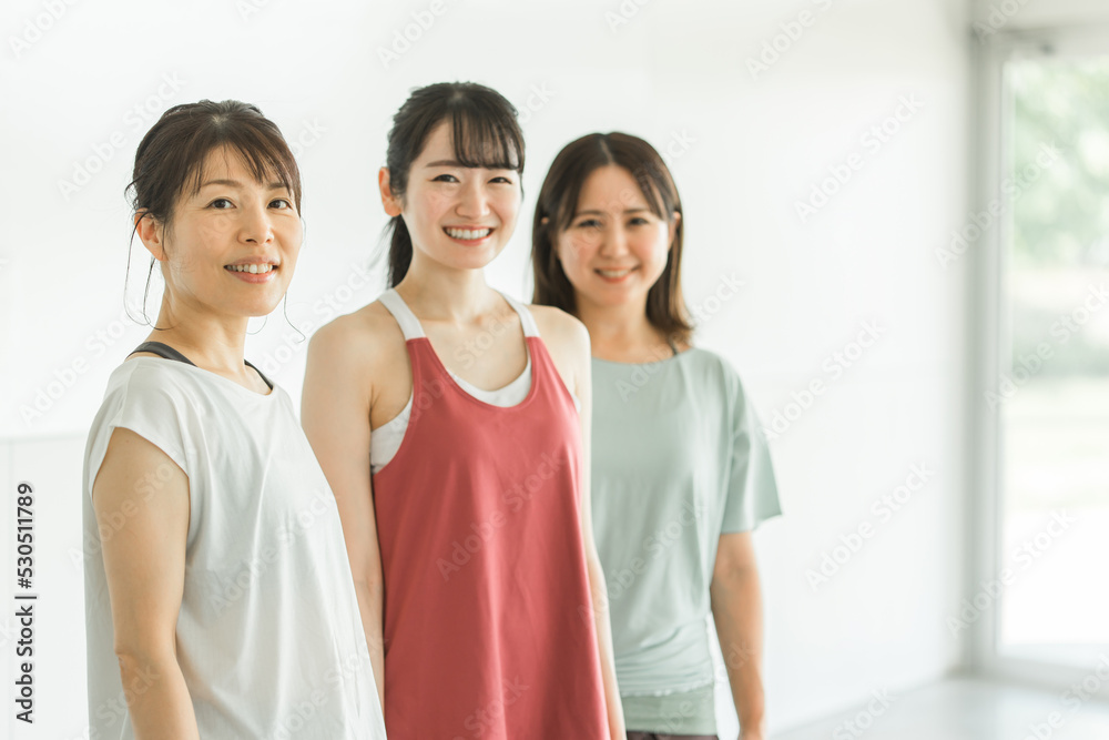 スポーツジムでスポーツウェアを着てトレーニングする女性達（カメラ目線）
