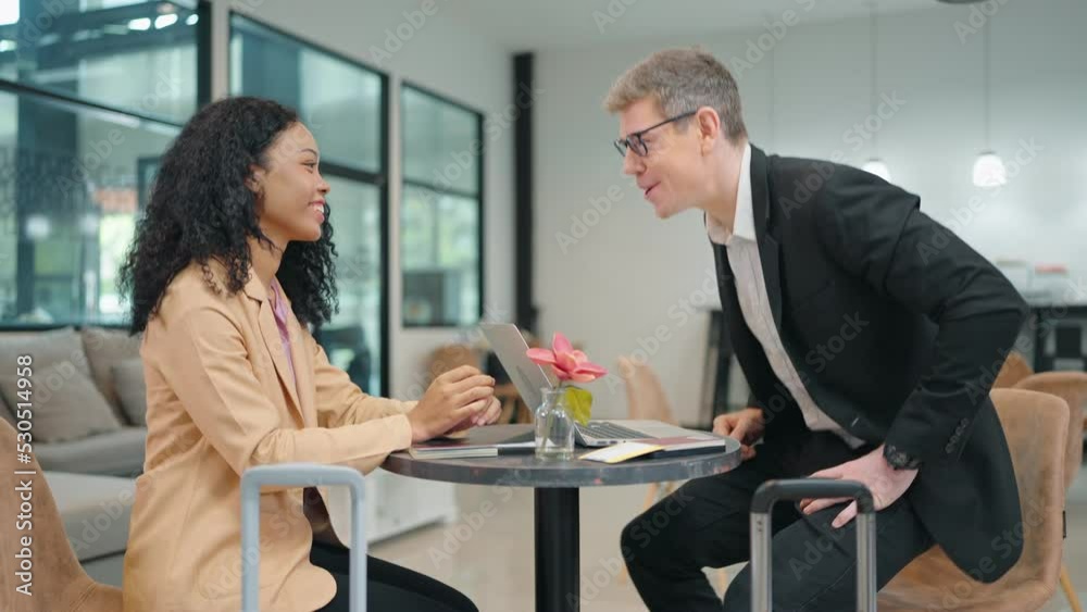 Businessman caucasian talking about the project consults and handshake with African American woman partner client making deal for collaboration at diverse business at airport lounge. Businessman caucasian talking about the project consults and handshake with African American woman partner client making deal for collaboration at diverse business at airport lounge.