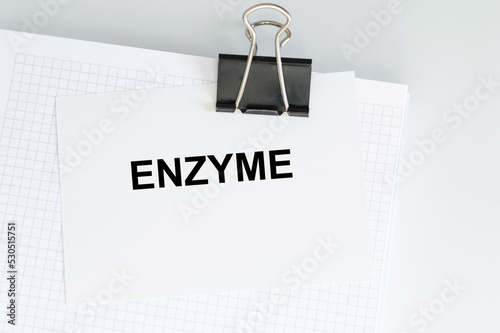 ENZYME text on a card clip to a notepad on a light background