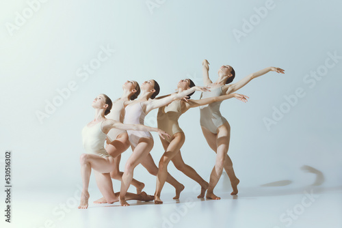 Group of young girls, ballet dancers performing isolated over grey studio background. Expression of freedom