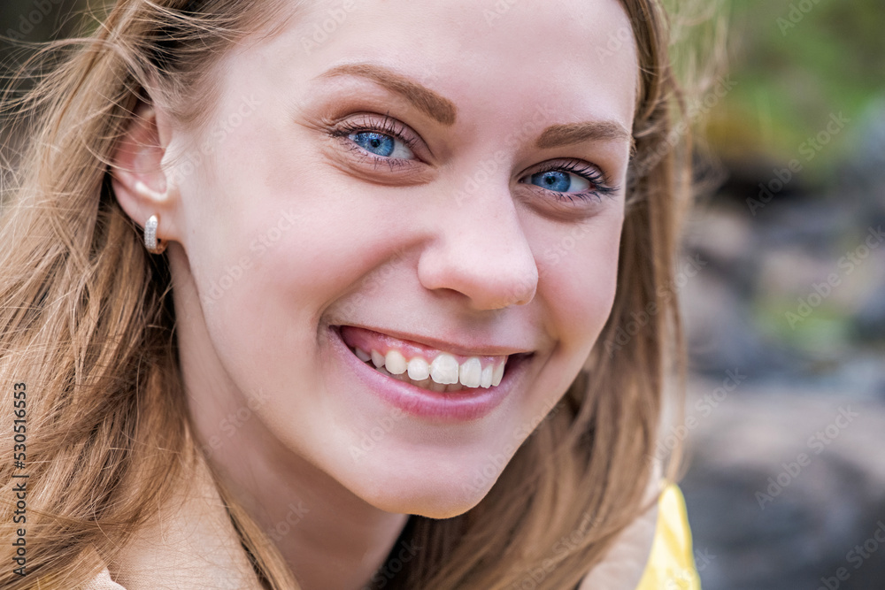 Portrait of young attractive blue-eyed woman looking at camera and smiling in yellow jacket. Selective focus