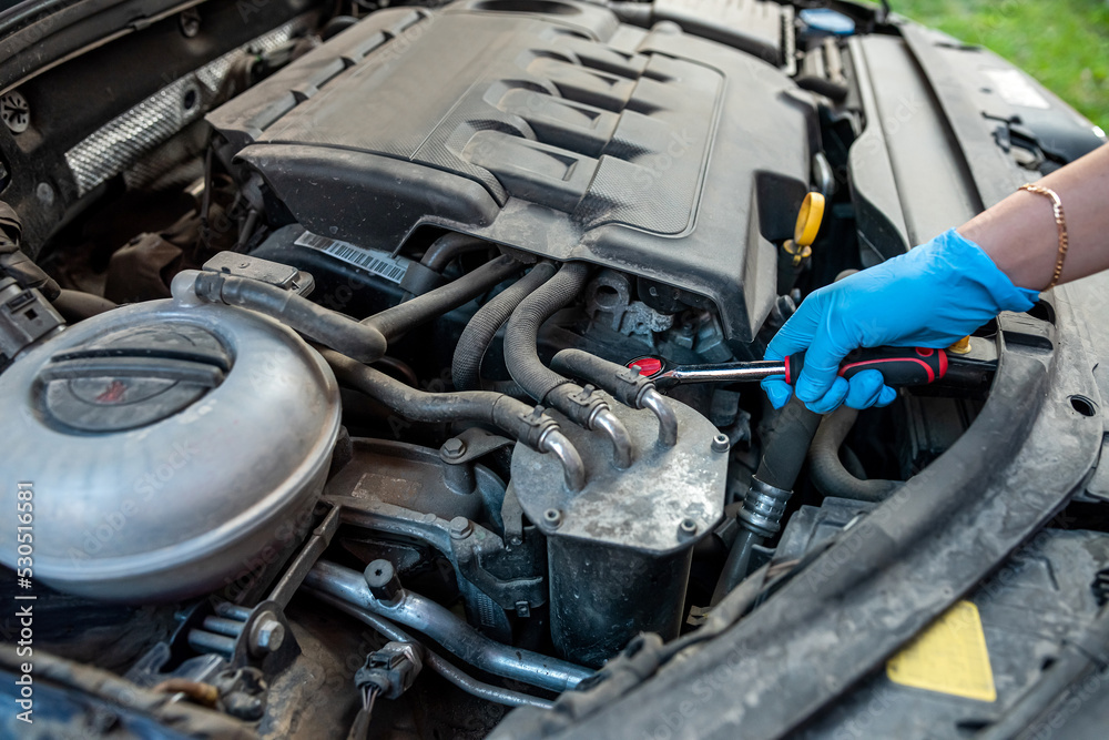 car mechanic or repairman repairs a car engine by hand in a car workshop with a wrench. car mechanic or repairman repairs a car engine by hand in a car workshop with a wrench.
