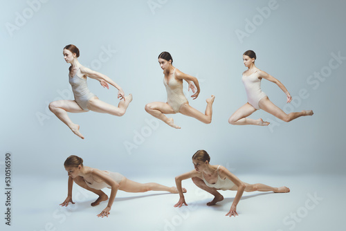 Group of young girls, ballet dancers performing, posing isolated over grey studio background. Jumping over