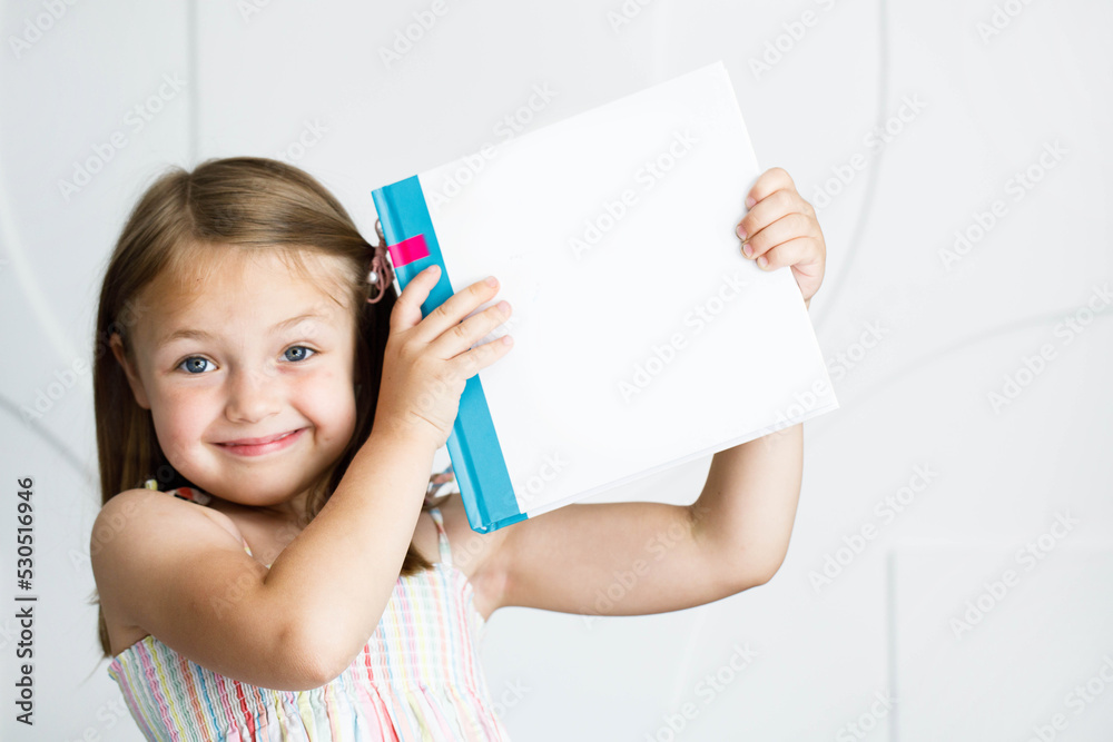 Książka dla dziecka z pustą okładką, dziewczynka trzyma książkę - obrazy, fototapety, plakaty 