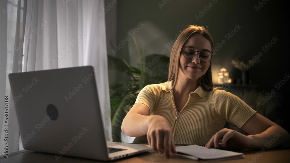 Woman have an idea doing online learning using note pad sitting at table in home interior.Young blonde girl using laptop for distance education indoors.Attractive female work remotely Woman have an idea doing online learning using note pad sitting at table in home interior.Young blonde girl using laptop for distance education indoors.Attractive female work remotely